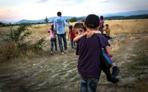 Menino sírio carrega irmão menor em direção à fronteira da Macedônia com a Grécia. Tragédia humanitária gravíssima